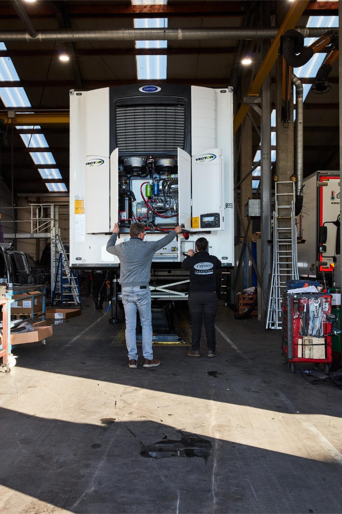 Two Westcool technicians at an opened Carrier Vector 1550 in the workshop